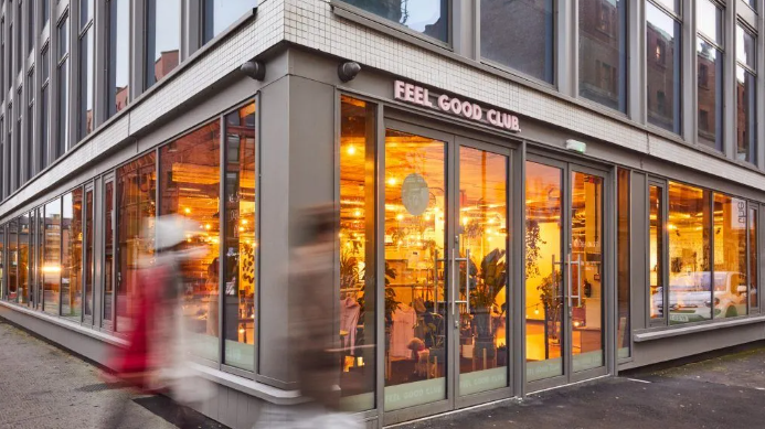 A person is walking in front of a building with a lot of windows.