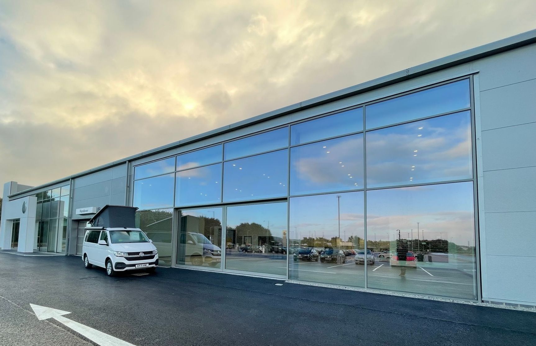 A white van is parked in front of a building with a lot of windows.