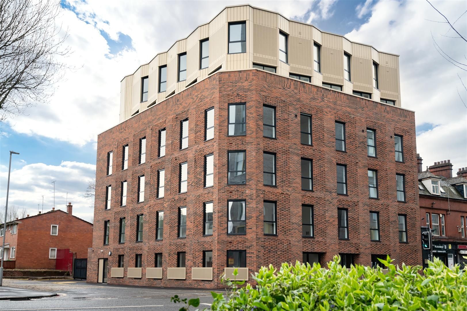 A large brick building with a lot of windows is sitting on the corner of a street.