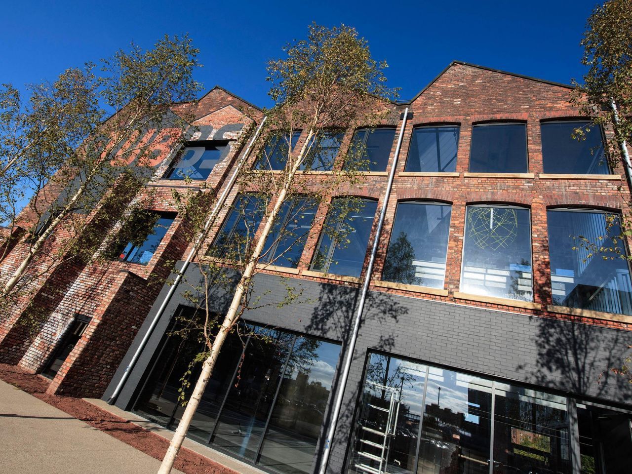 A large brick building with lots of windows and trees in front of it.