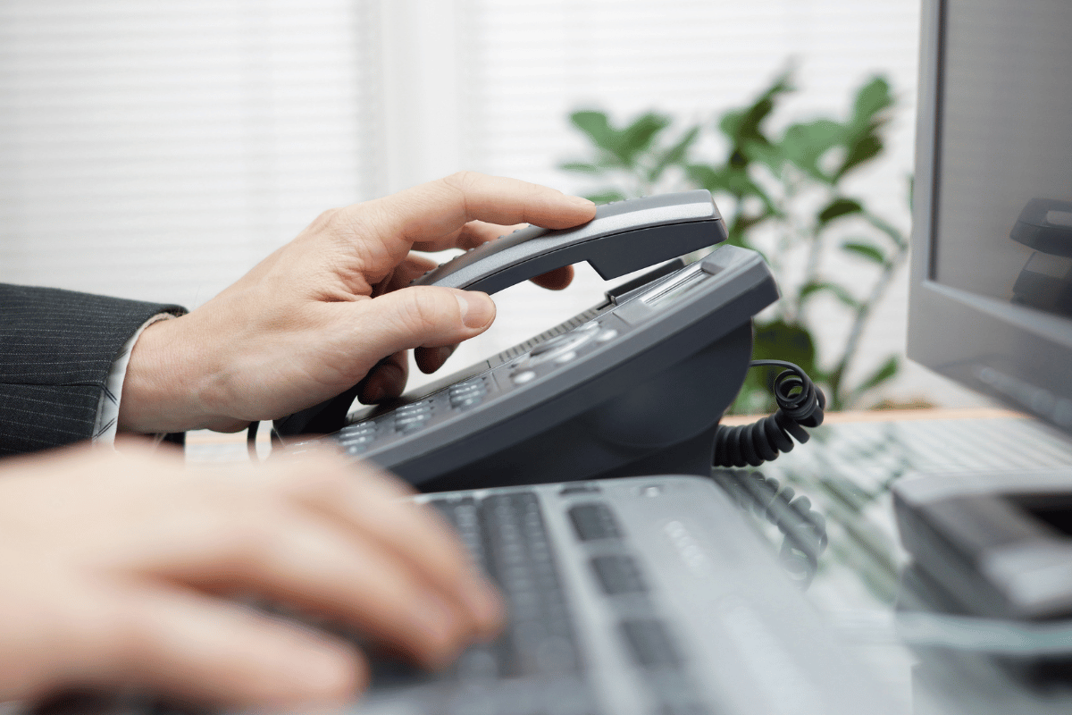 A person is using a telephone while typing on a keyboard