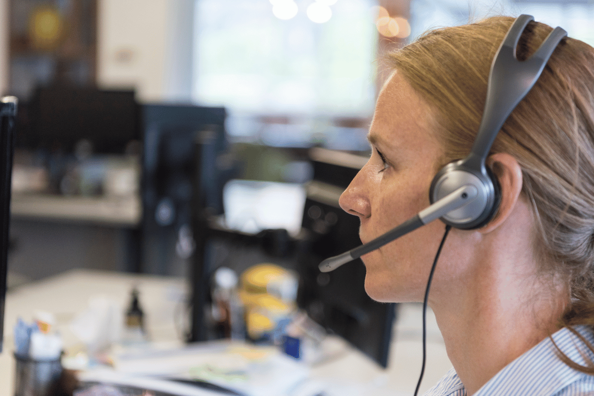 A woman wearing a headset is sitting in front of a computer.