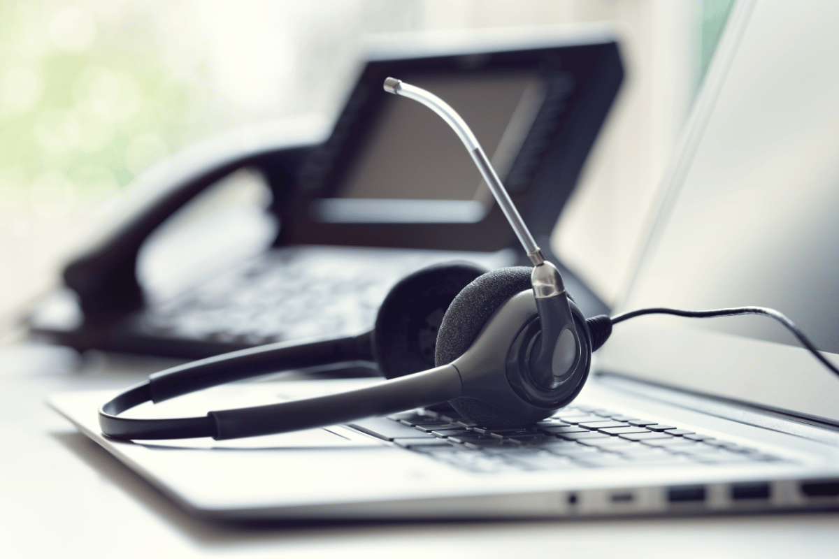 A headset is sitting on a laptop next to a phone