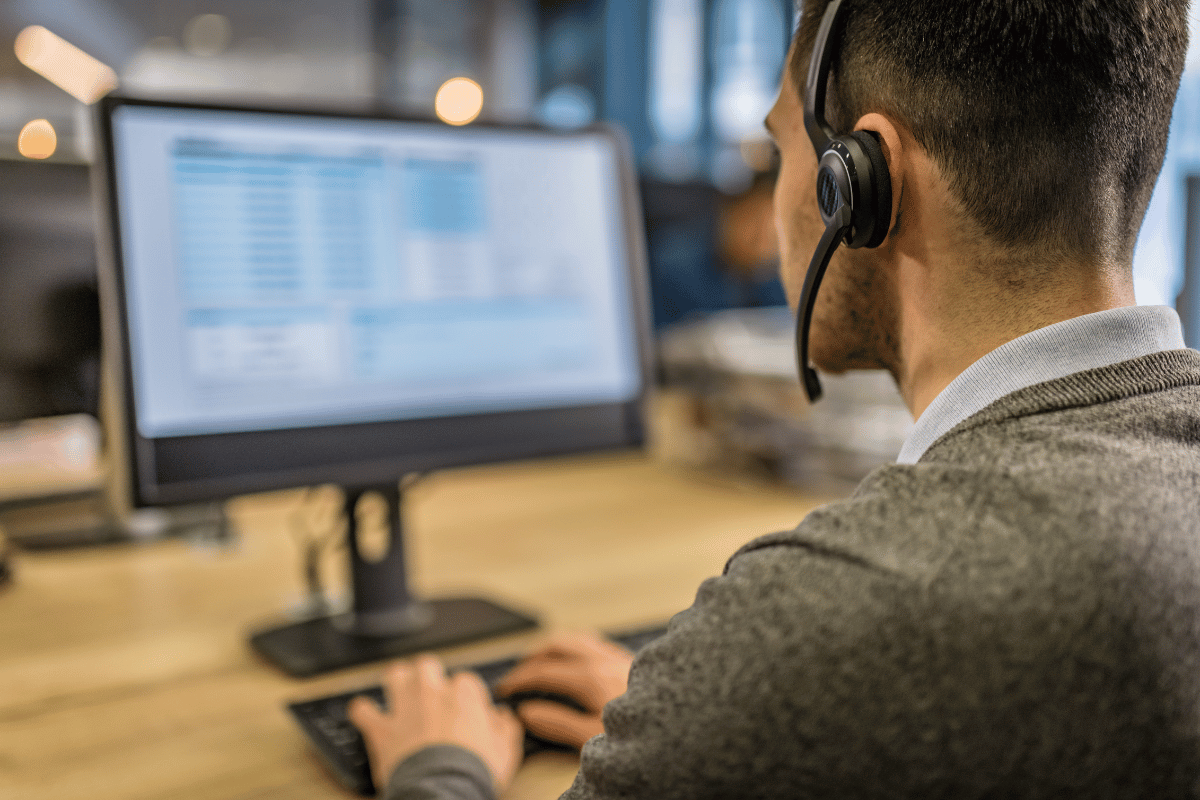 A man wearing a headset is sitting in front of a computer.