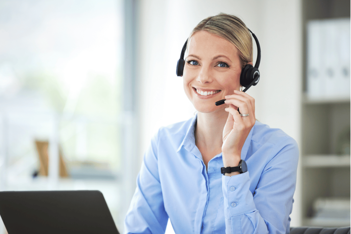 A woman wearing a headset is sitting in front of a laptop computer.