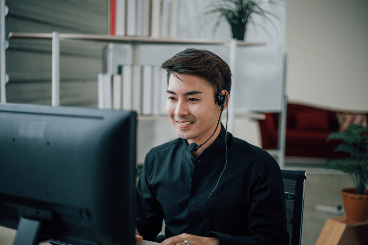 A man wearing a headset is sitting in front of a computer.