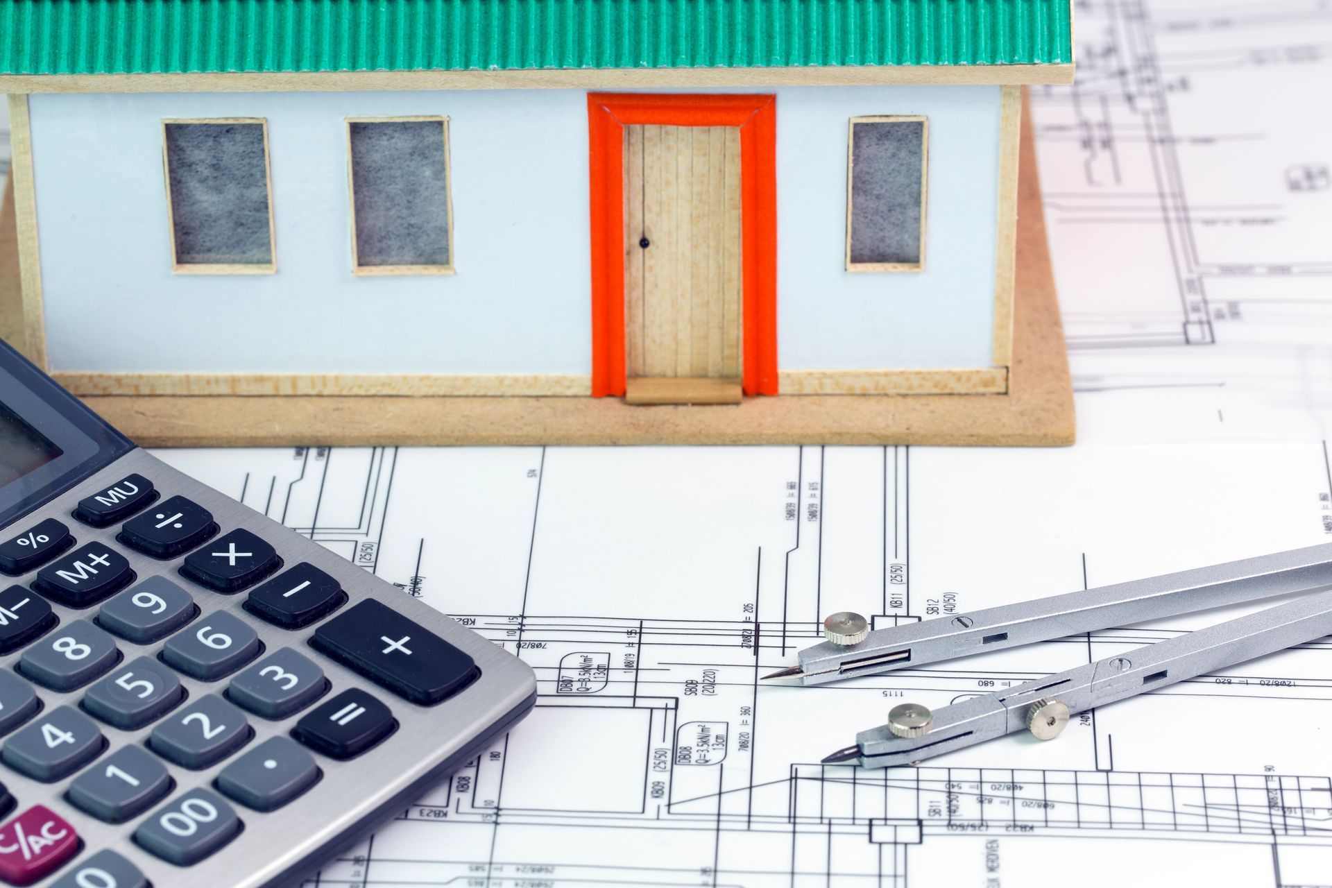 Un modello di casa è seduto accanto a una calcolatrice e una bussola