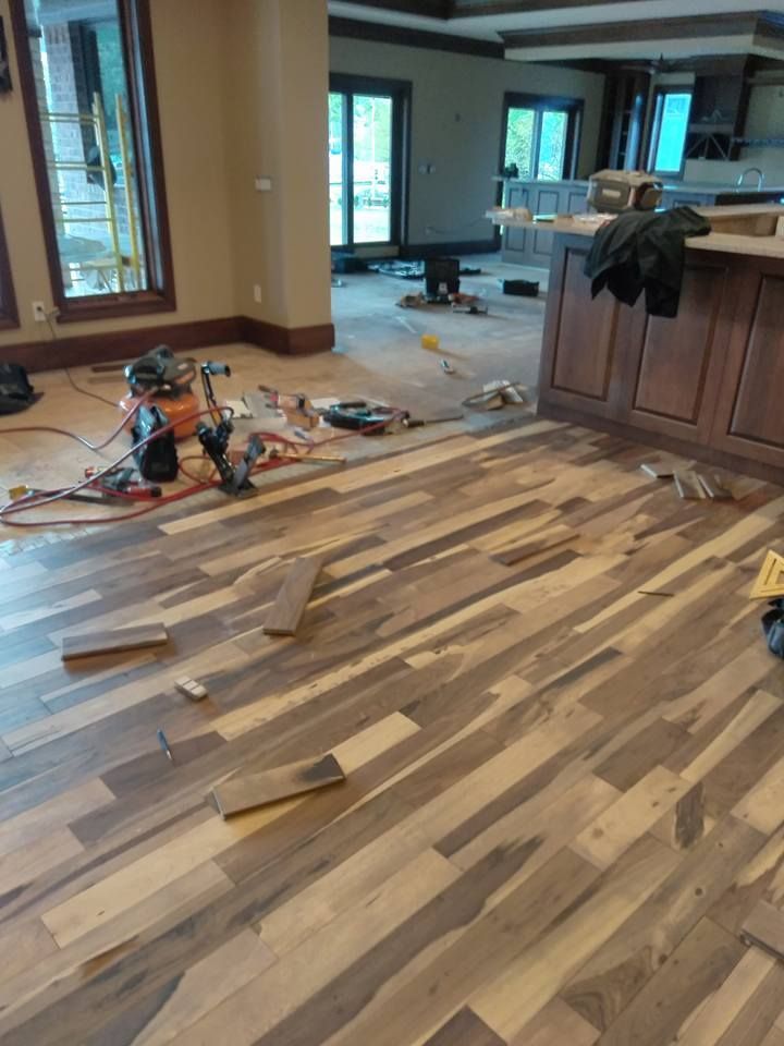 Hardwood flooring installation in progress; tools and materials scattered.