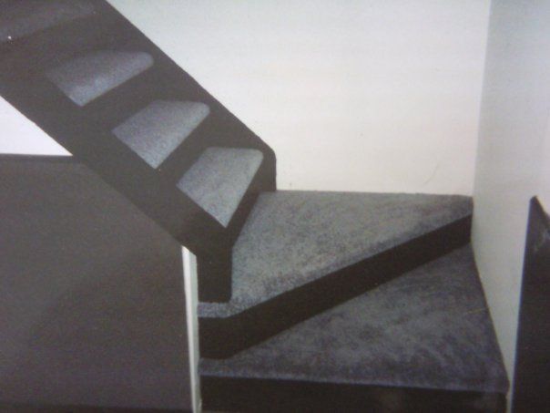 Dark stairs with gray carpet, ascending and turning, next to white walls.