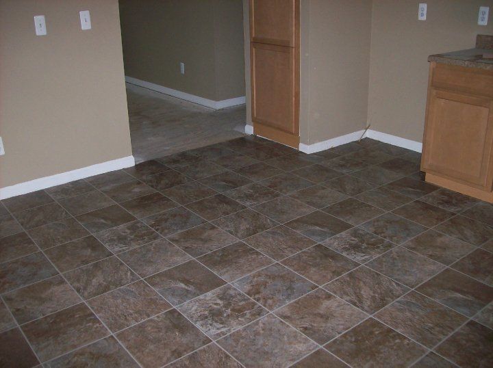 Brown tile floor, beige walls, and light brown cabinets in a room.