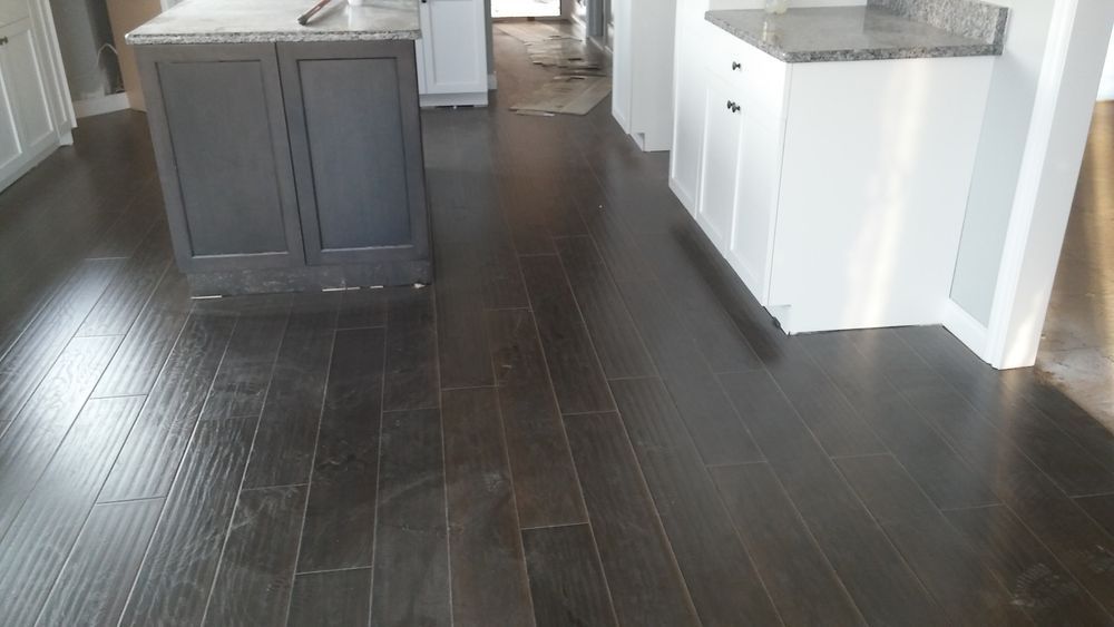 Dark stained hardwood floor in a kitchen setting, with gray and white cabinets and countertops.