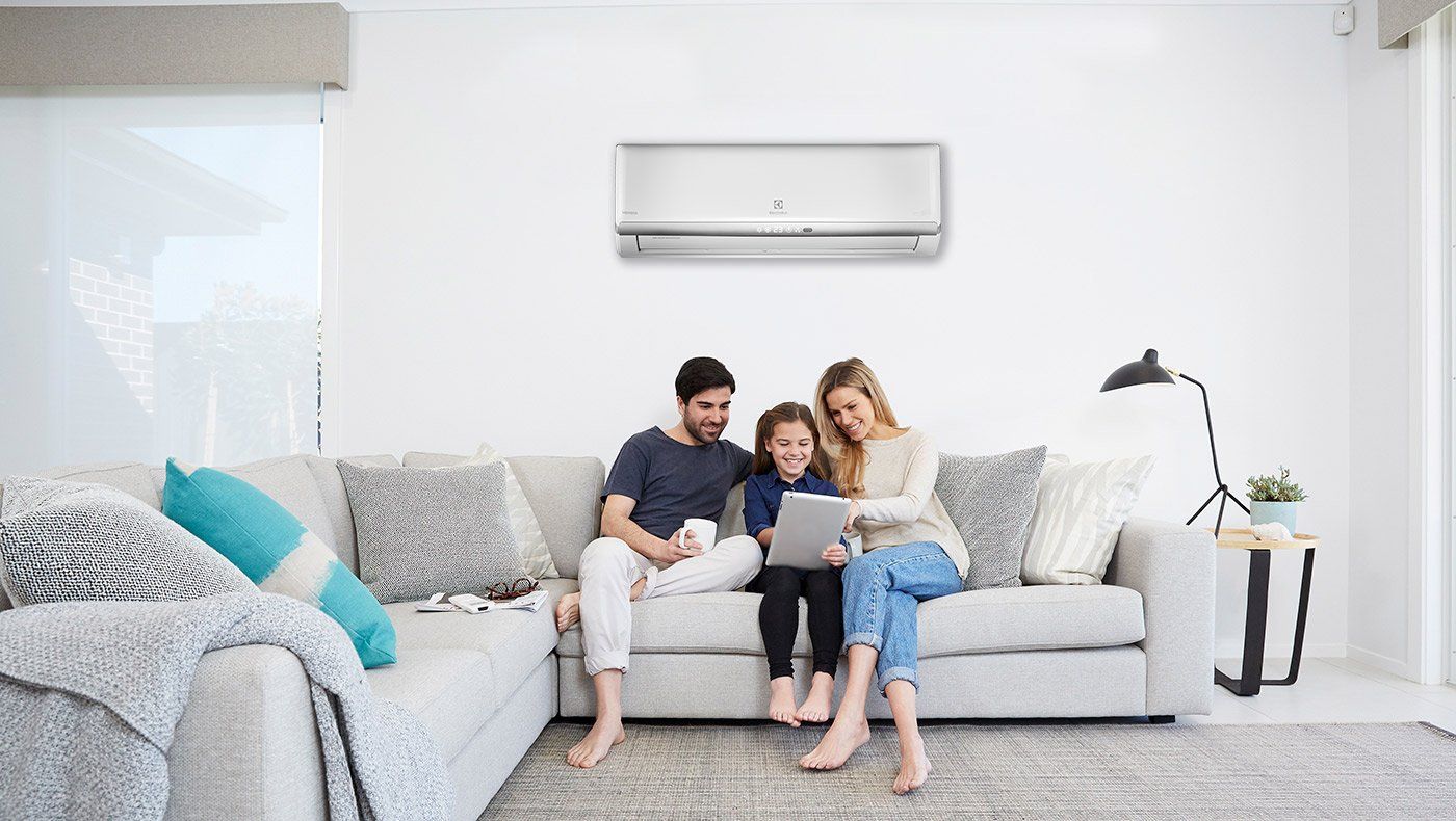 A family is sitting on a couch in a living room looking at a laptop.