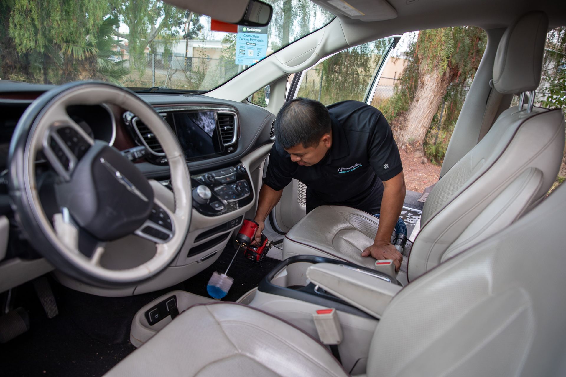 A man is cleaning the interior of a car with a vacuum cleaner.