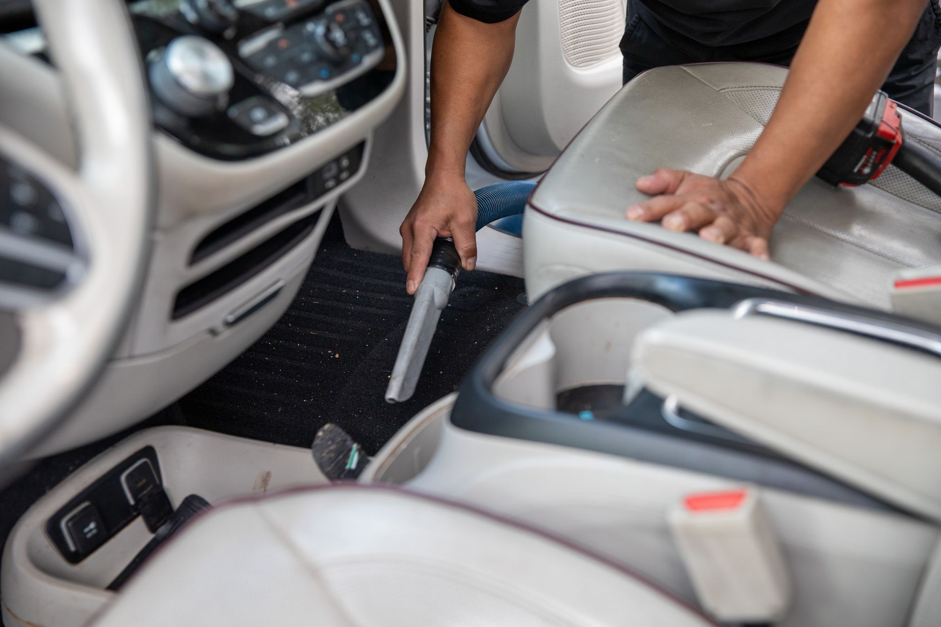 A person is cleaning the interior of a car with a vacuum cleaner.