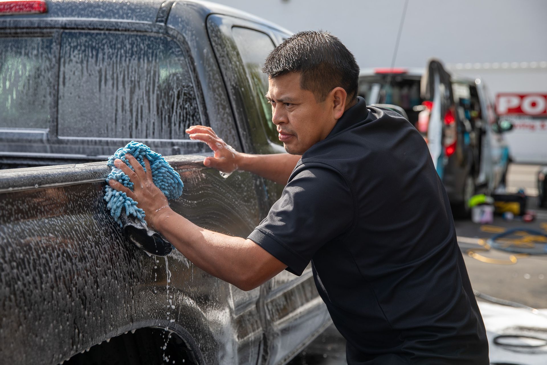 A man is washing a truck with a towel.