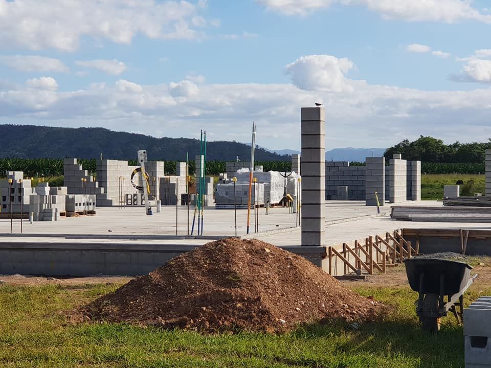 Construction site: concrete block walls being built; pile of dirt and wheelbarrow in foreground.— Ionspark Electrical in Atherton, QLD