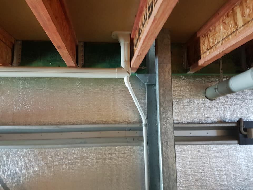 Underside view of building structure with exposed wooden beams, metal framing, insulation, and pipes.— Ionspark Electrical in Atherton, QLD