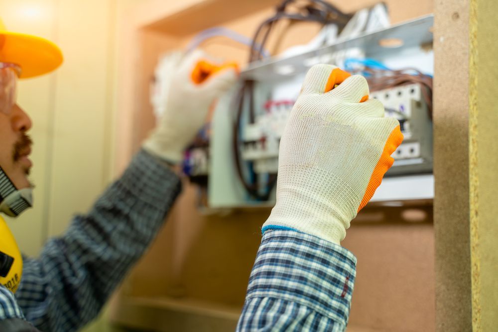 Electrician Working on a Circuit Breaker, Wearing Gloves and a Hard Hat — Ionspark Electrical in Dimbulah, QLD