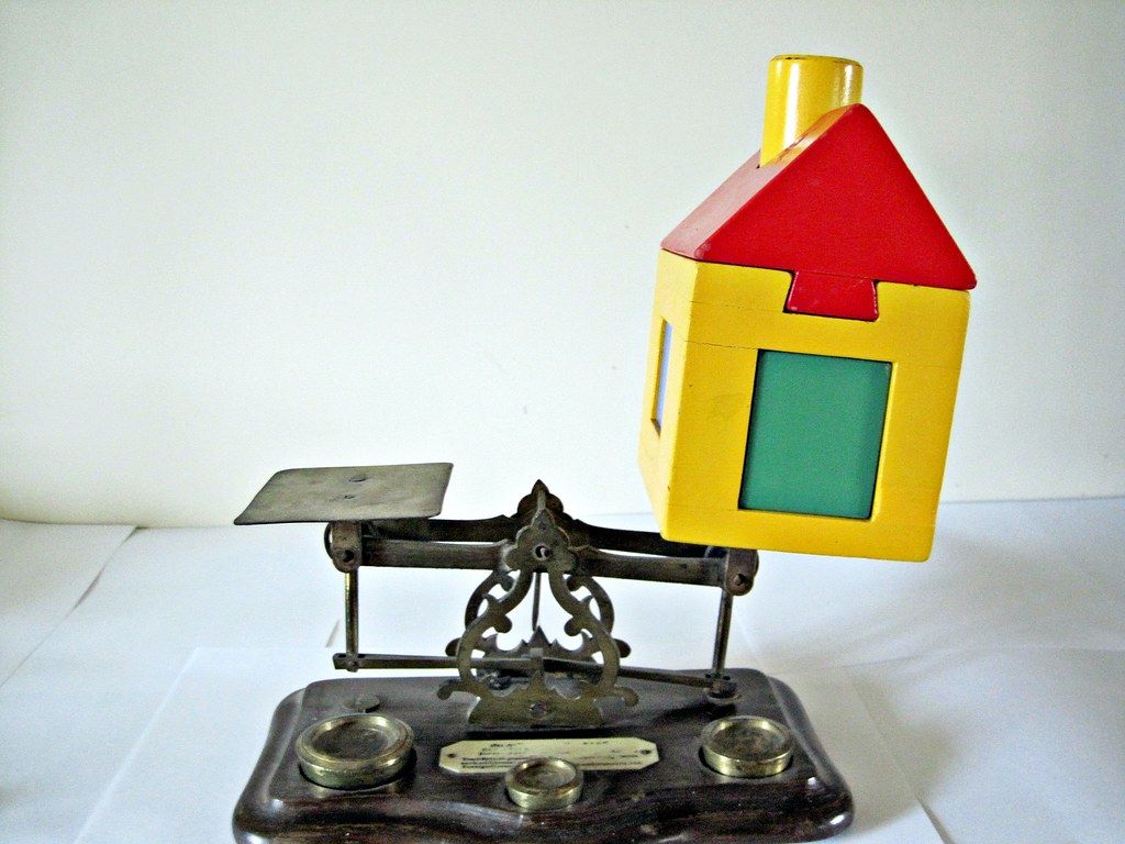 A scale with a yellow house on top of it