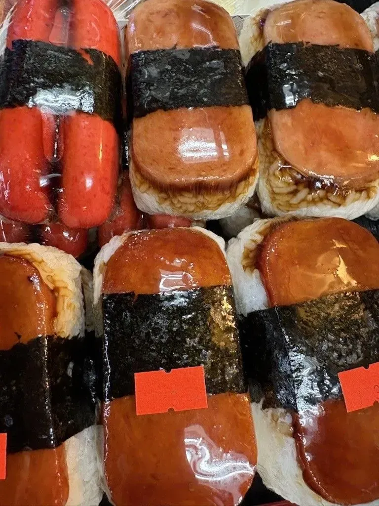 Spam musubi: grilled spam on rice, wrapped with seaweed, and a red price tag.