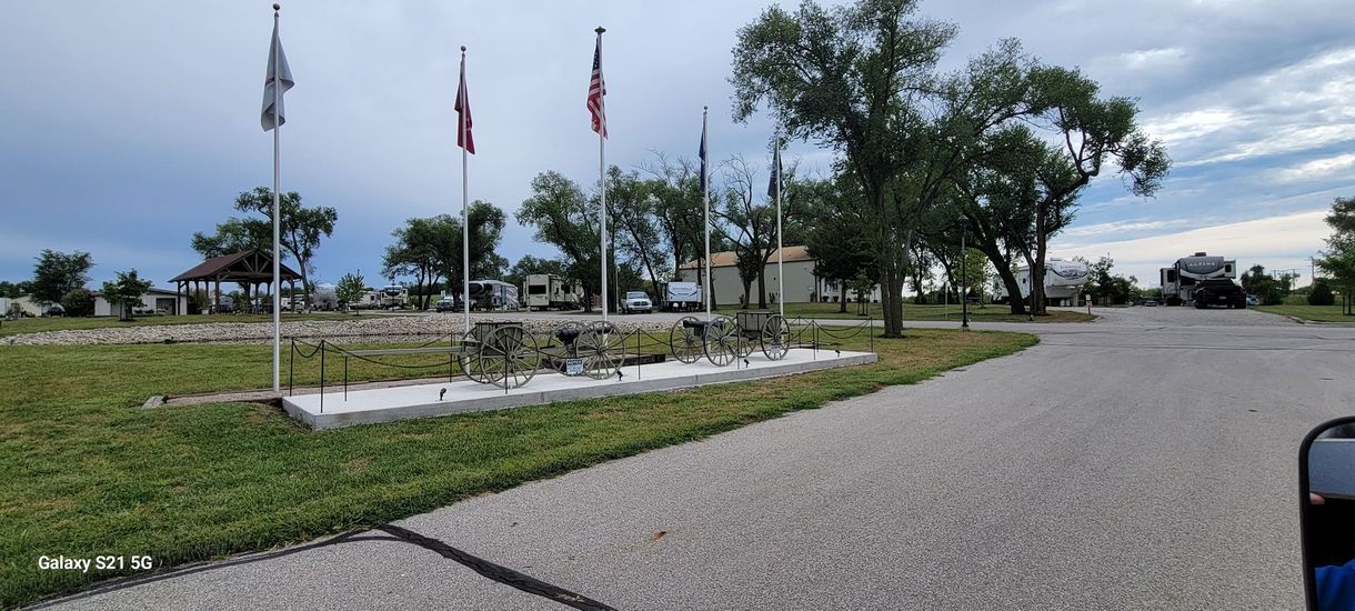 A gravel road leading to a park with flags flying in the wind.