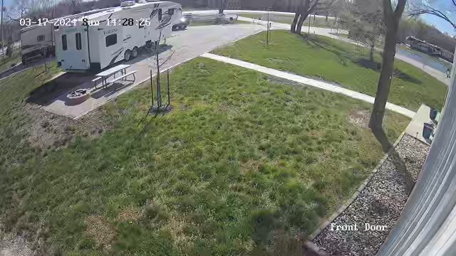 A rv is parked in a grassy area next to a path.