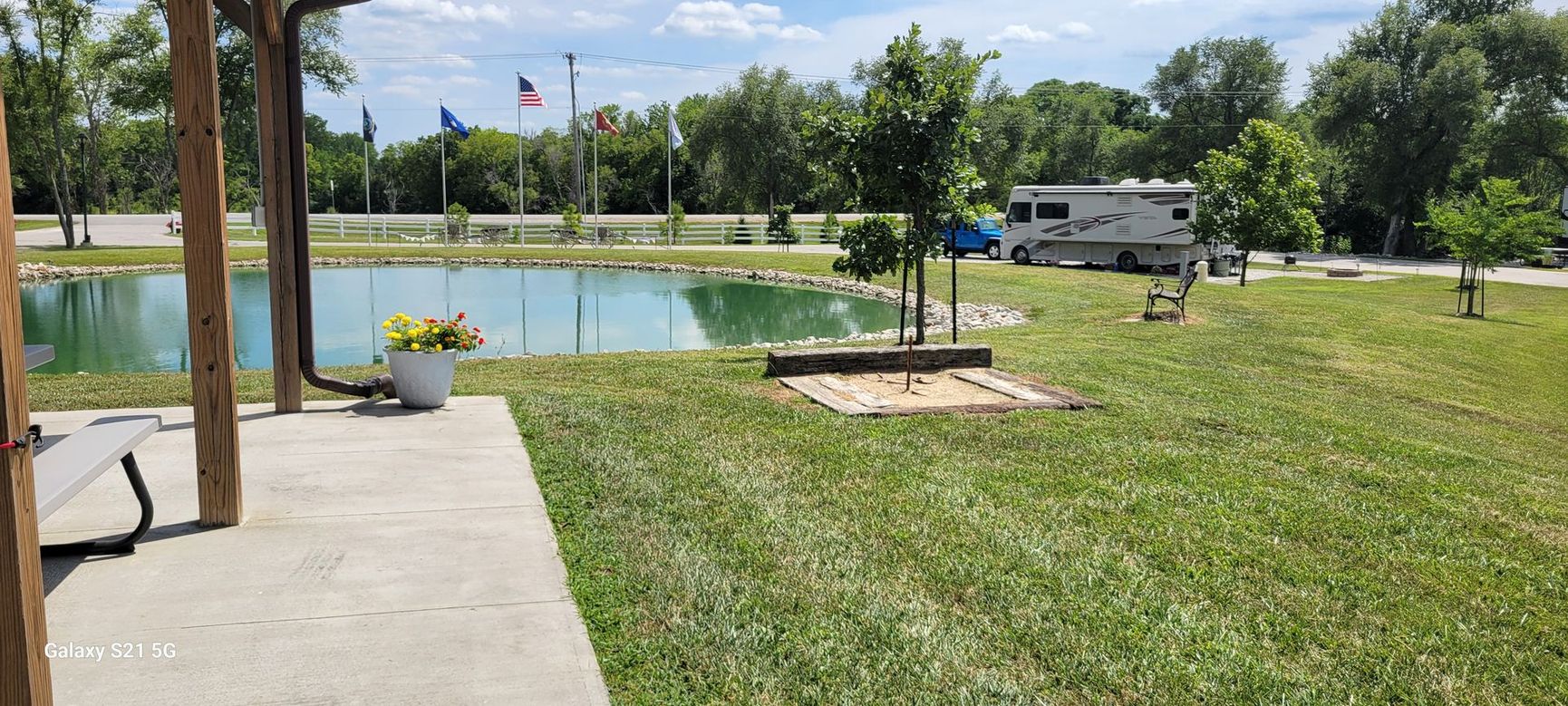 A rv is parked in a grassy area next to a pond.