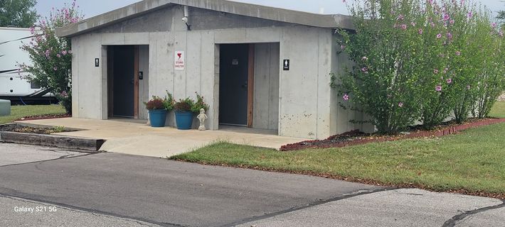 A concrete building with two toilets and two potted plants in front of it.