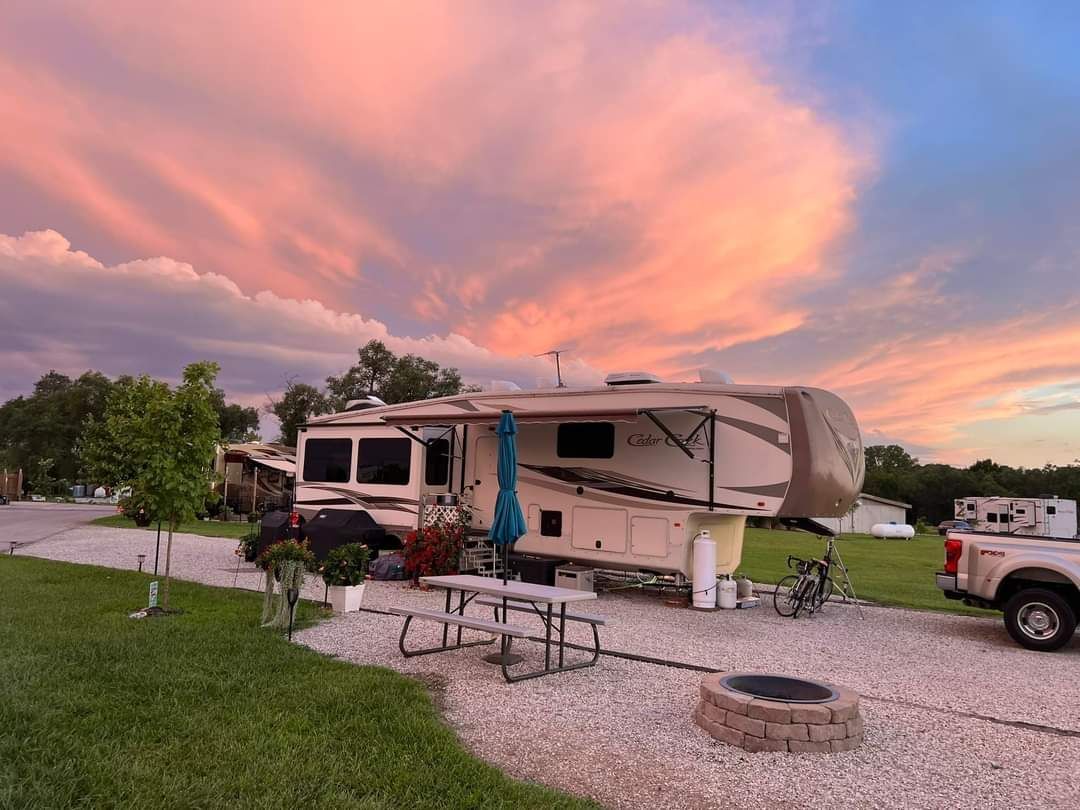 A rv is parked in a gravel lot at sunset.