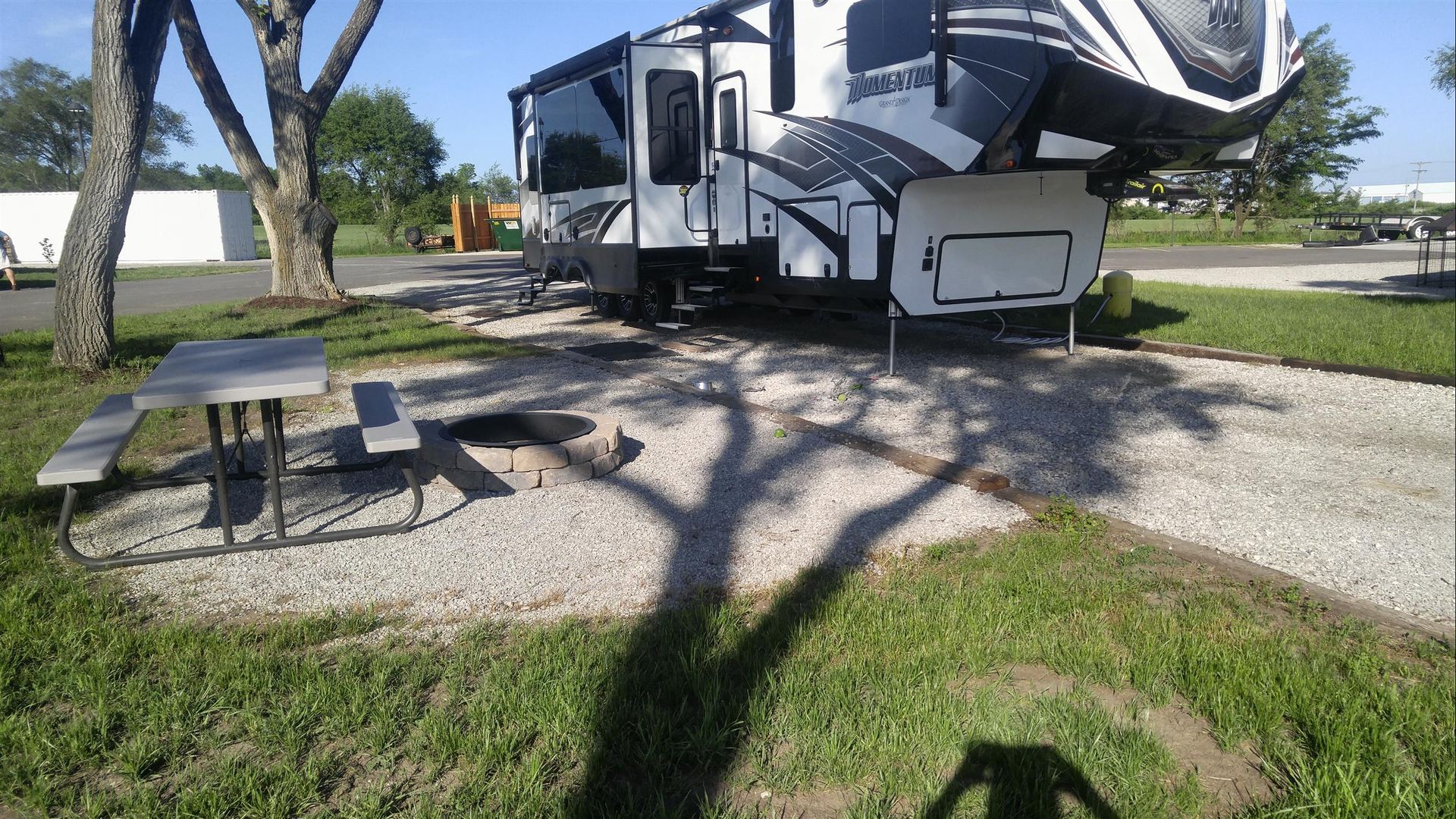 A rv is parked in a grassy area next to a picnic table.