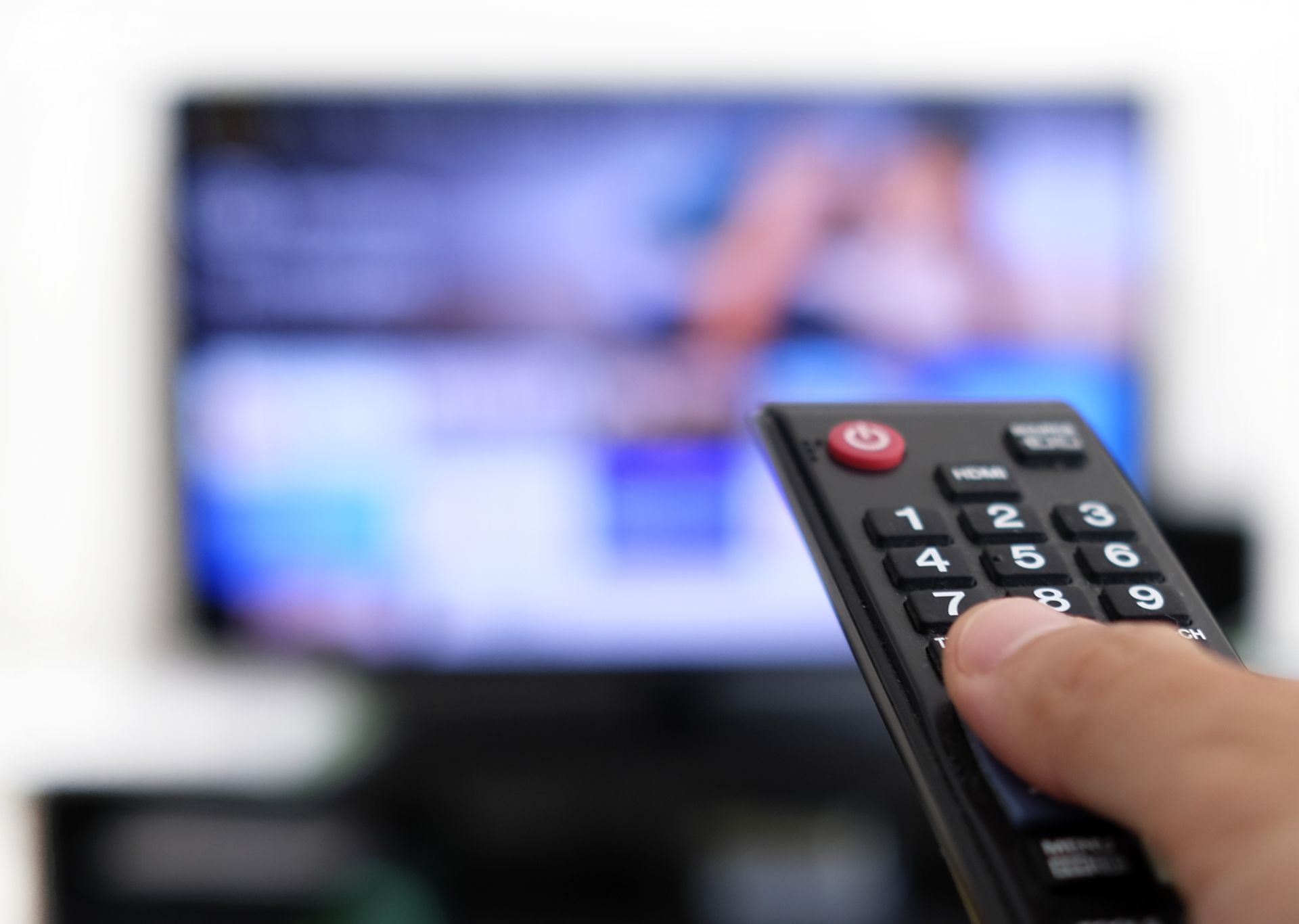 A person is holding a remote control in front of a television