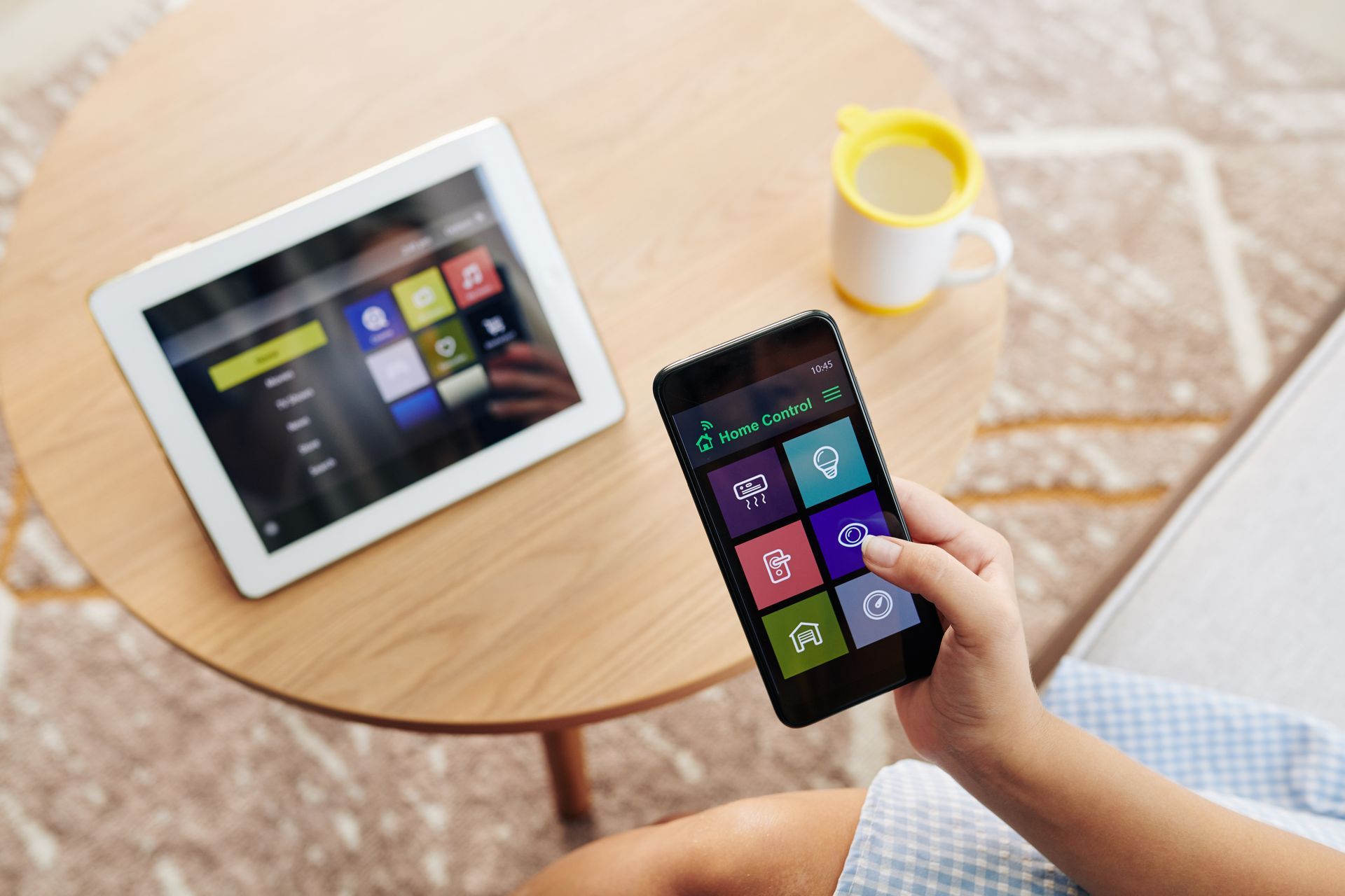 A person is holding a cell phone in front of a tablet.