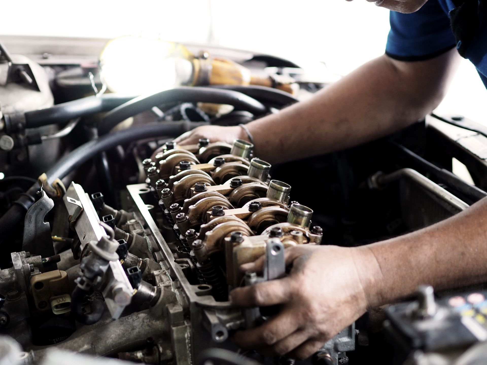 Mechanic working on car engine with exposed cylinder head in a garage