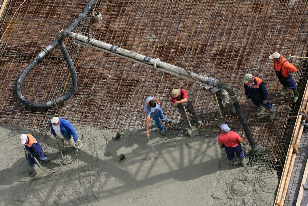 A Group Of Construction Workers Are Working On A Concrete Floor — Lonnie Henderson Concreting In Kurri Kurri, NSW