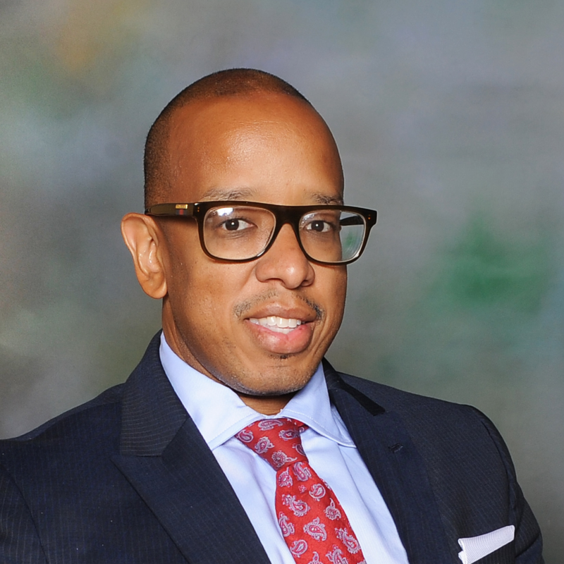 A person with shoulder-length brown hair and a neutral expression looking directly ahead against a plain light background.