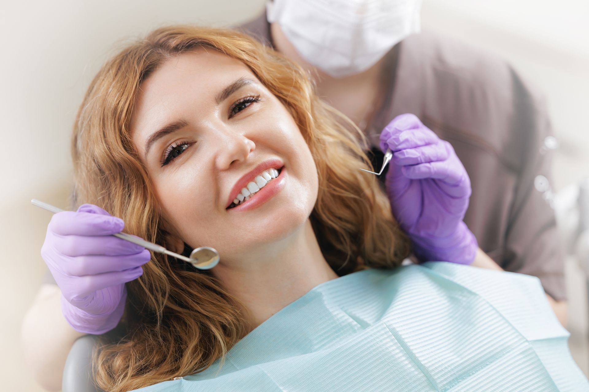 Happy patient smiling during a dental exam with expert cosmetic dentists at a modern clinic.
