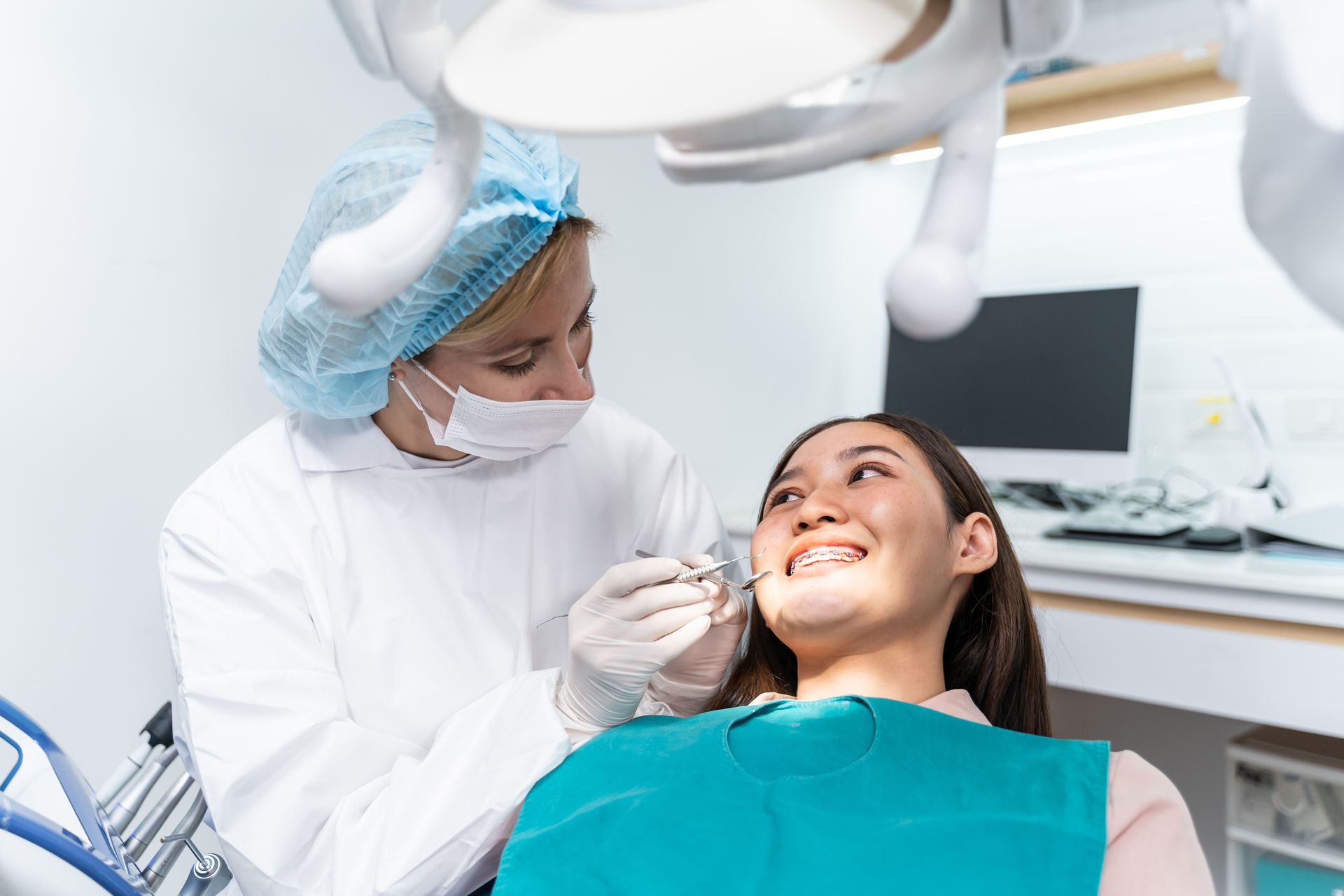 Dentist examining a patient's teeth under a bright light in a dental office.