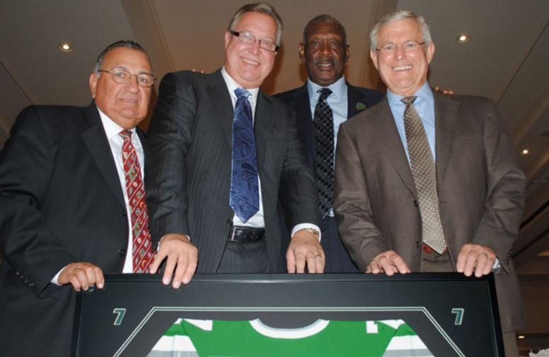 Four men in suits and ties are posing for a picture