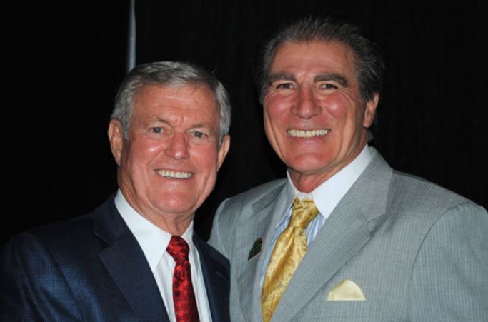 Two men in suits and ties are posing for a picture