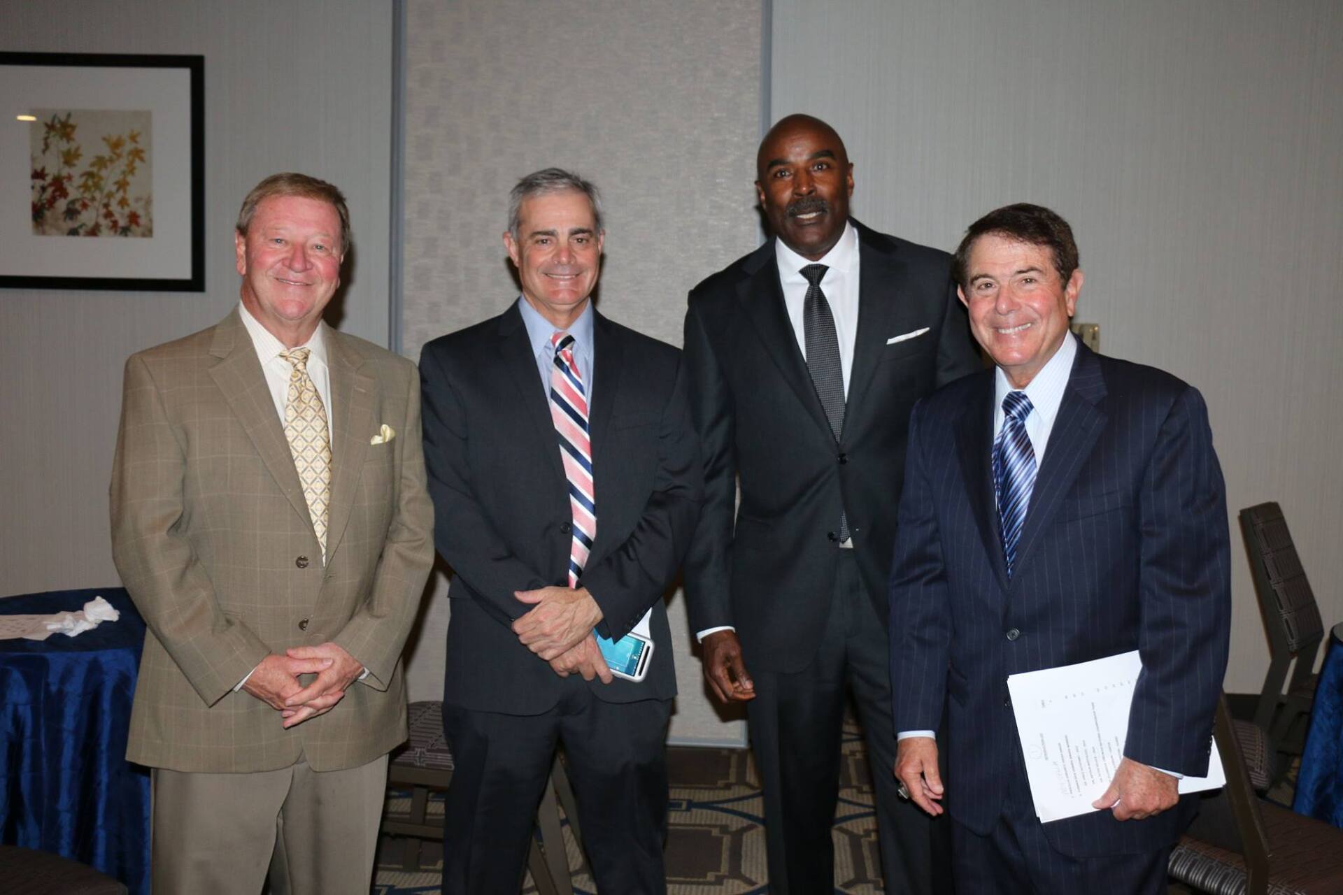Four men in suits and ties pose for a picture