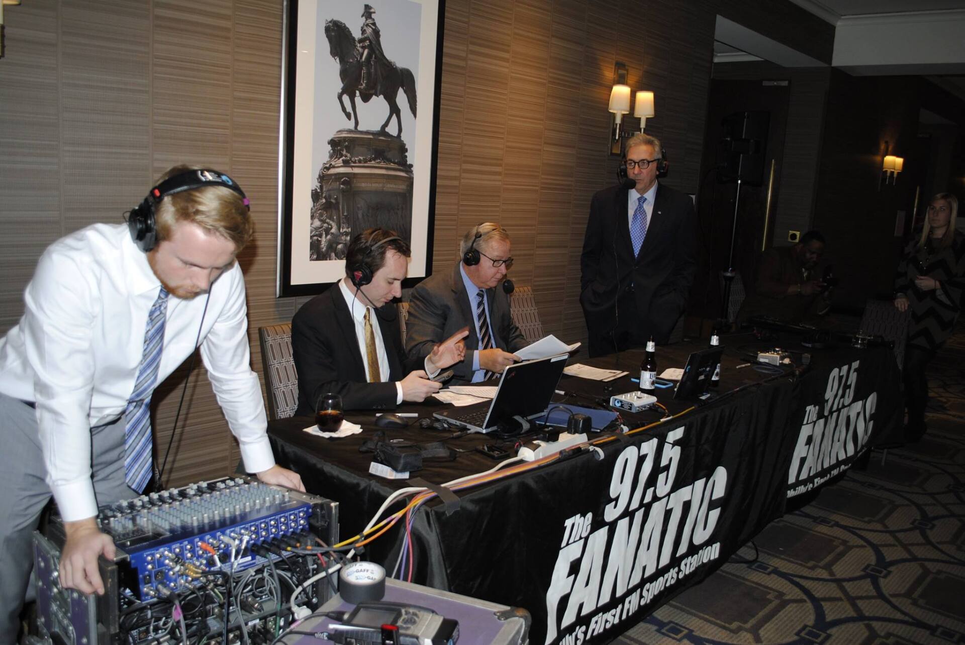 A group of men are sitting at a table with a sign that says 97.9 the fanatic