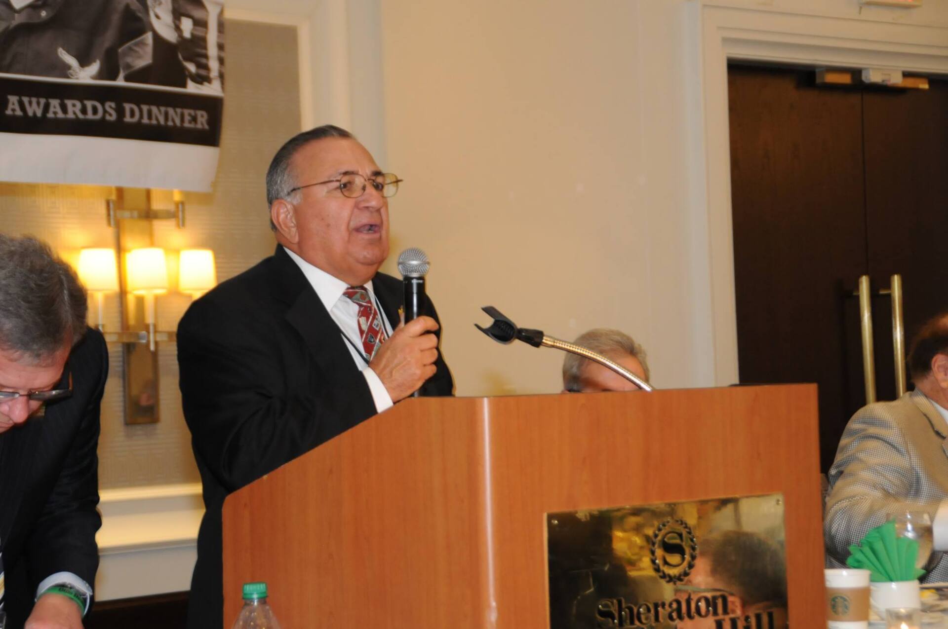 A man stands behind a podium that says sheraton on it