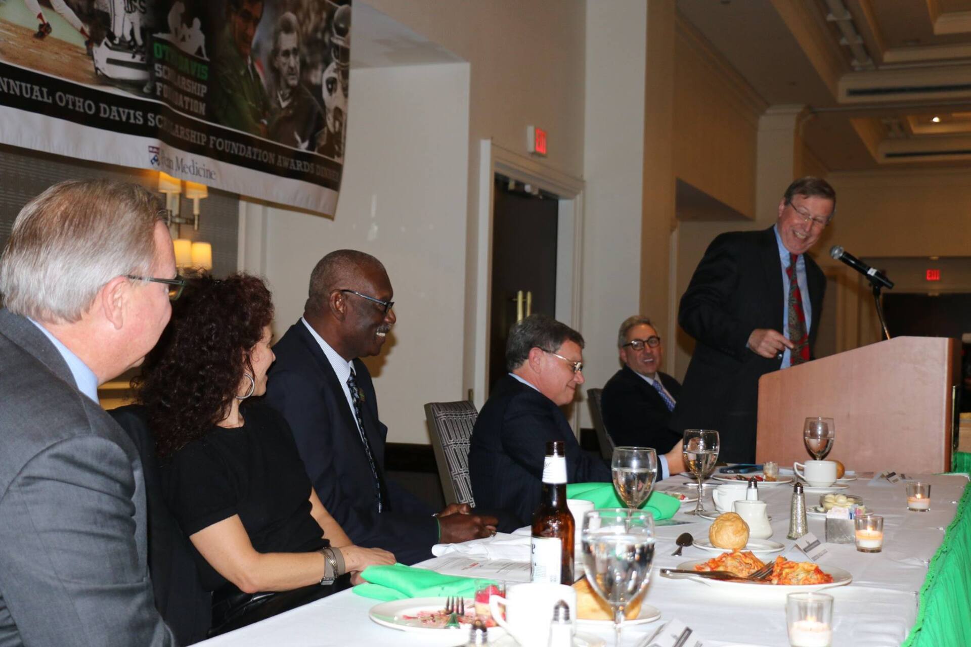 A man is giving a speech to a group of people at a table