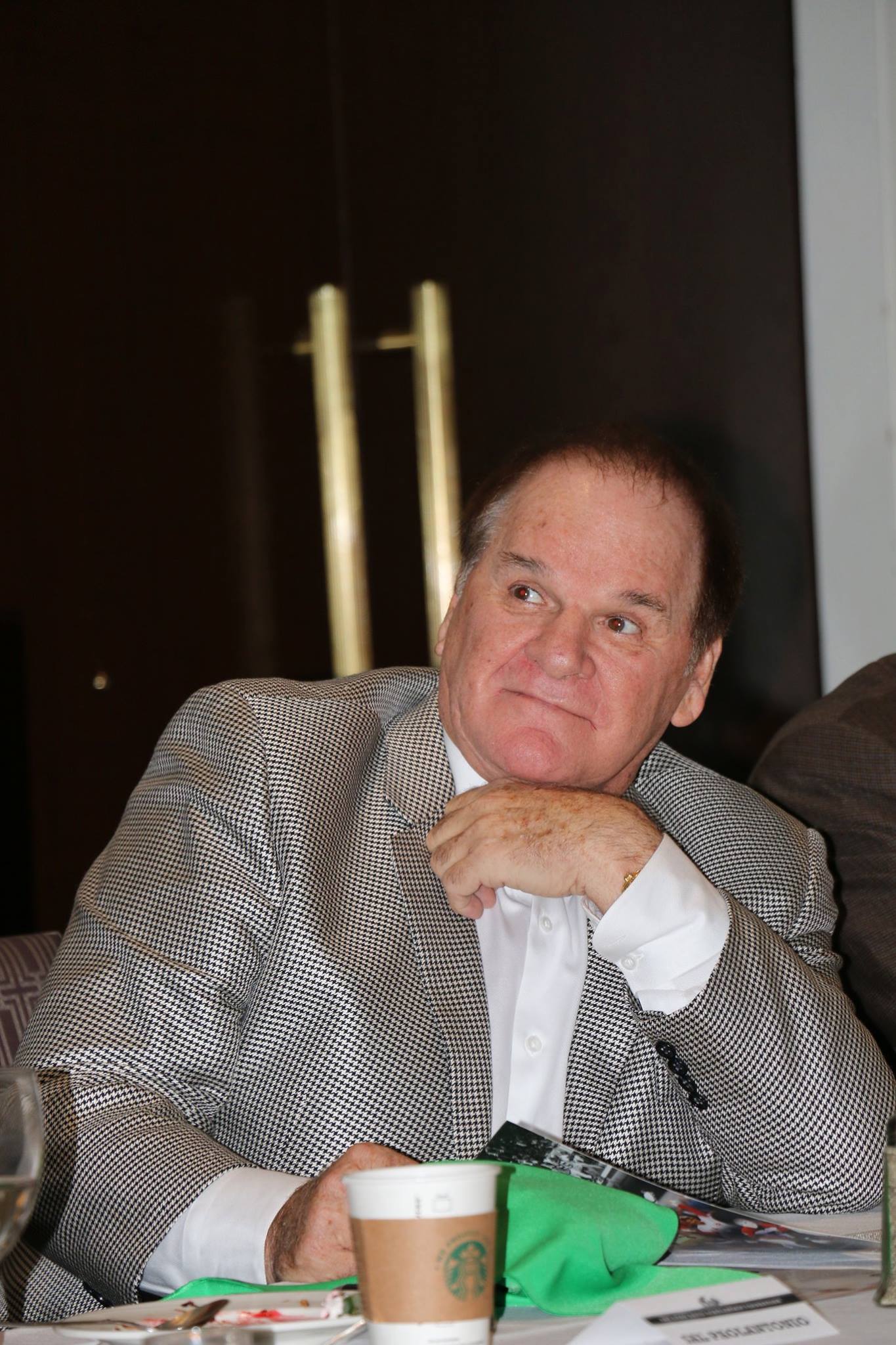 A man in a zebra print jacket is sitting at a table with a starbucks cup.