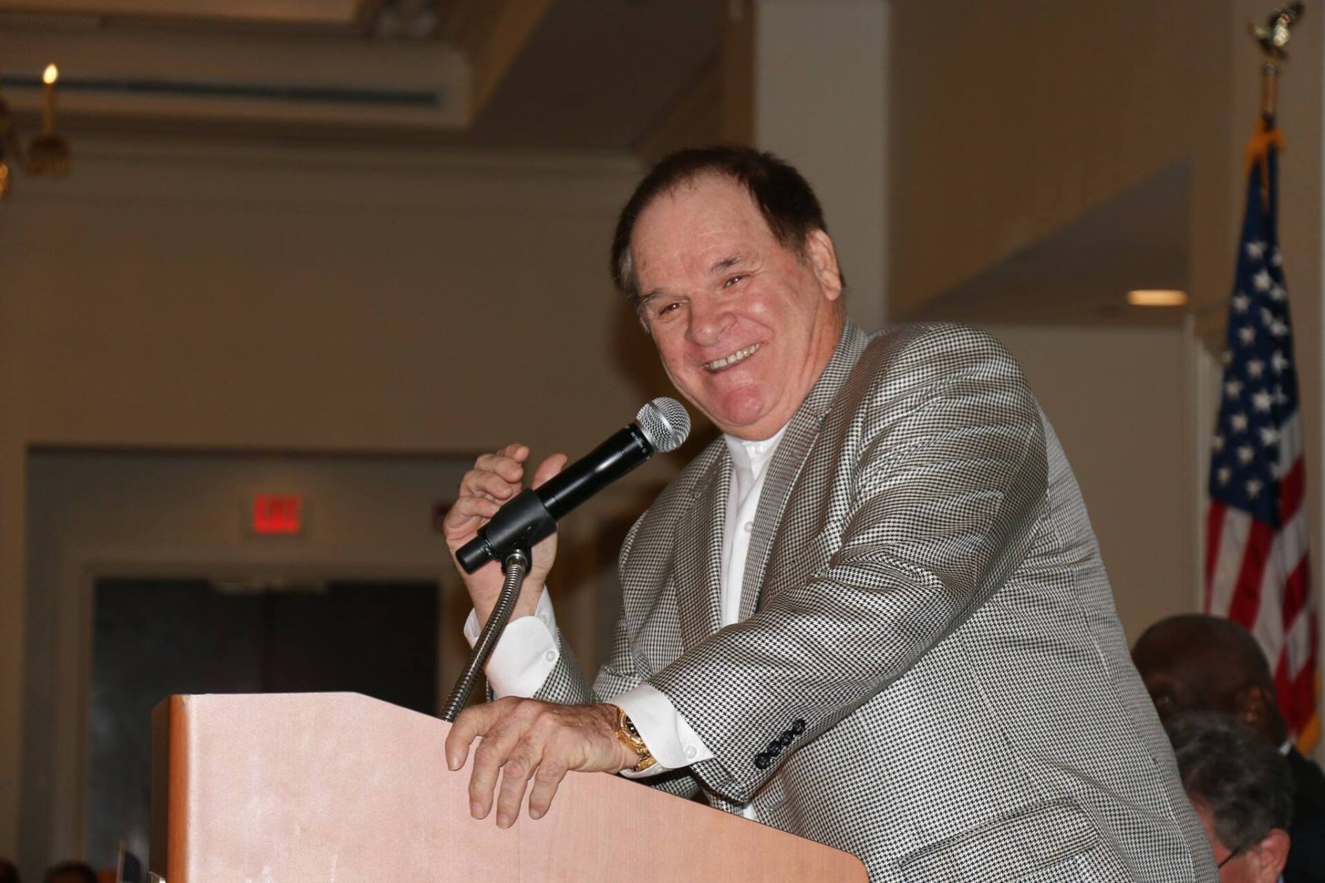A man stands at a podium holding a microphone and smiling