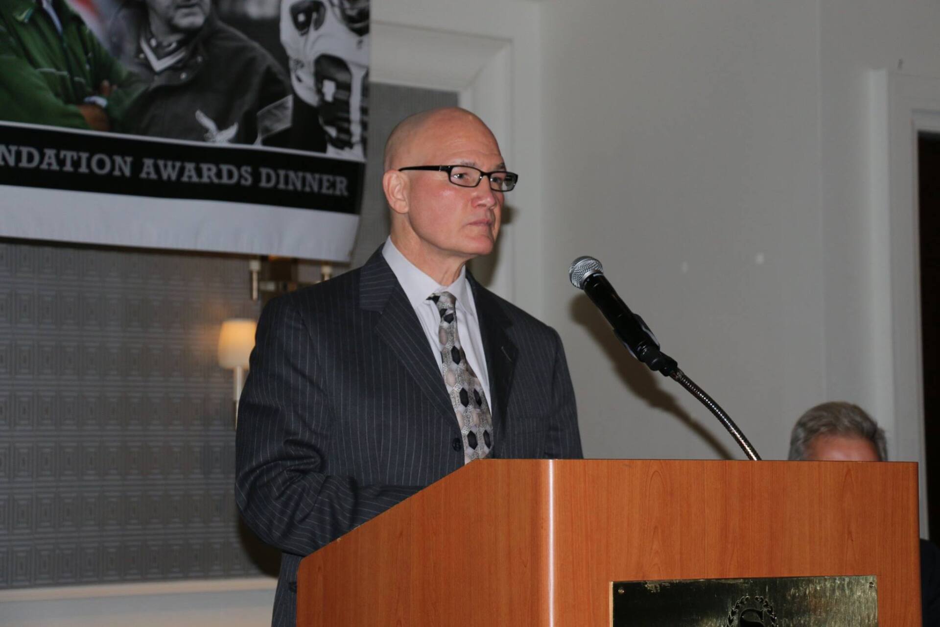 A man stands at a podium with a sign behind him that says foundation awards dinner