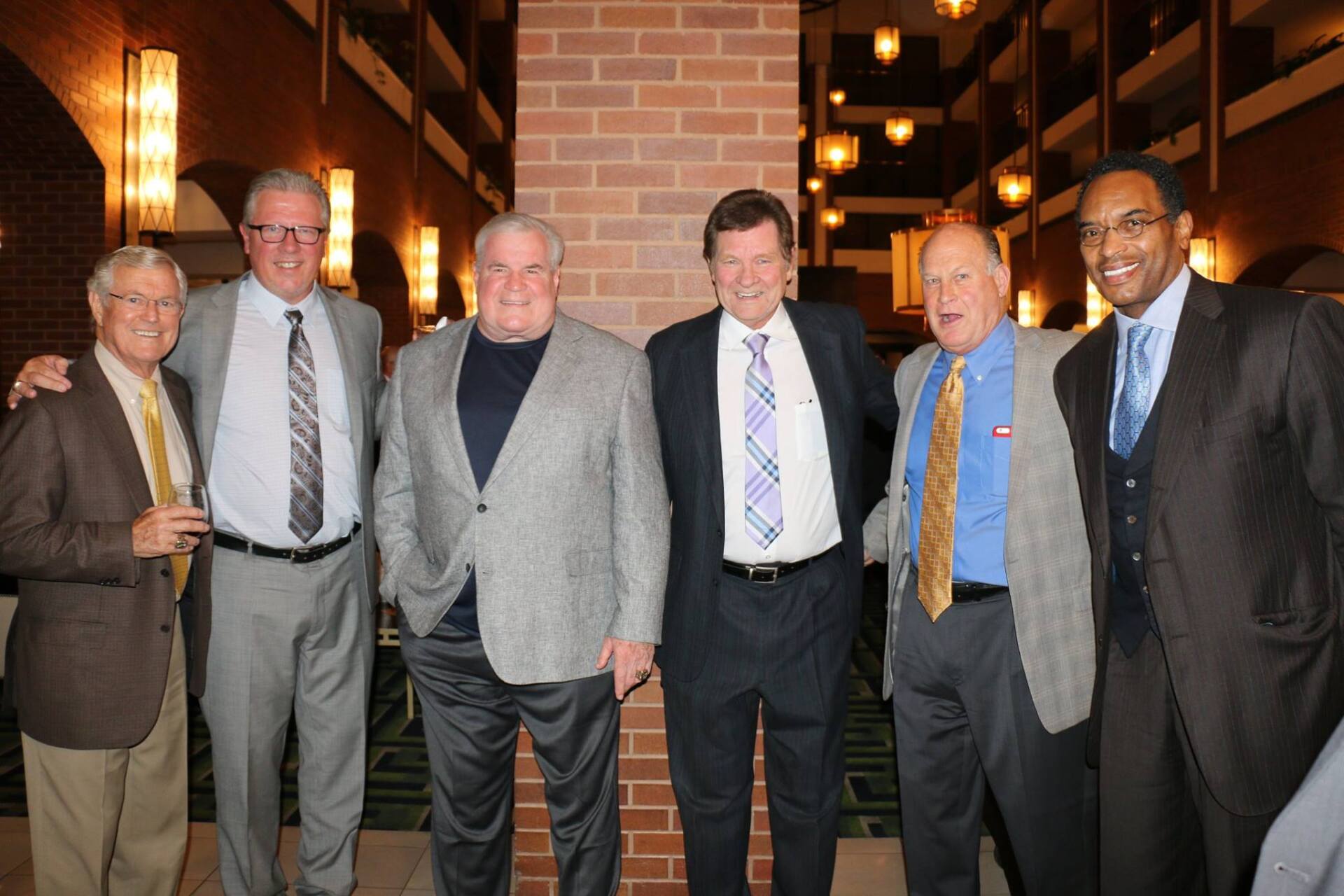 A group of men posing for a picture in front of a brick wall