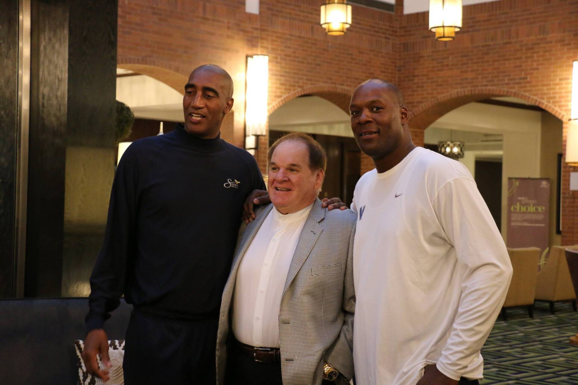Three men are posing for a picture in a hallway