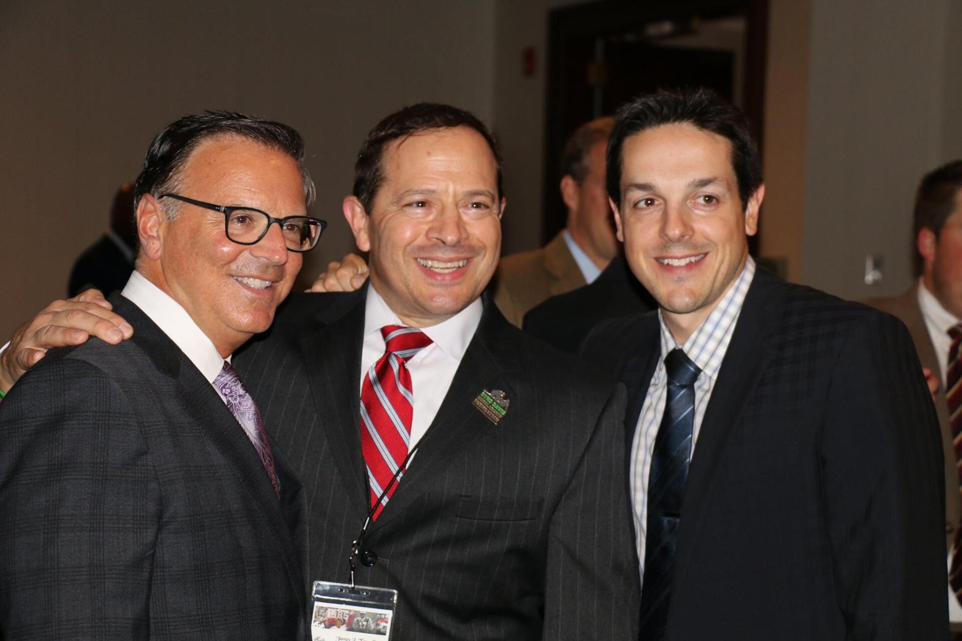 Three men in suits and ties are posing for a picture