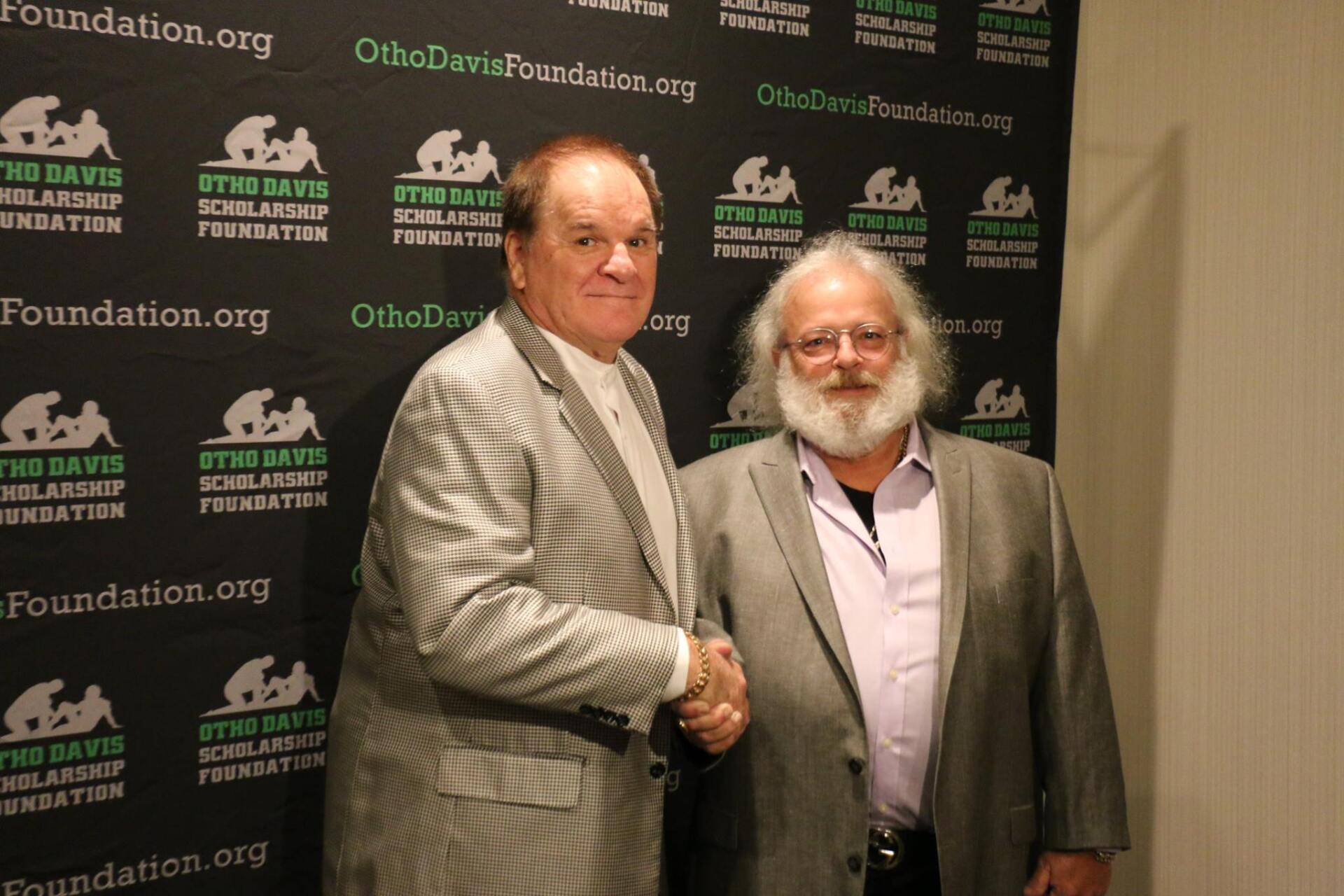 Two men shaking hands in front of a sign that says foundation.org